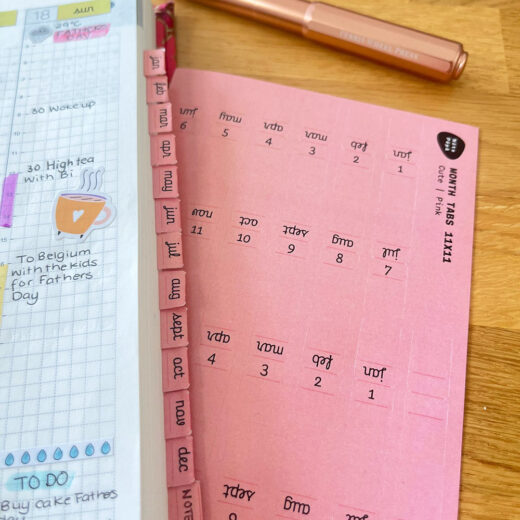 Real use Noto Pepa Peachy Pink Abbreviated Month Tabs Stickersheet Cute style on Hobonichi planner, scene on wooden desk with copper pen